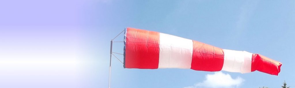 Red and white aviation windsock blows in the wind.