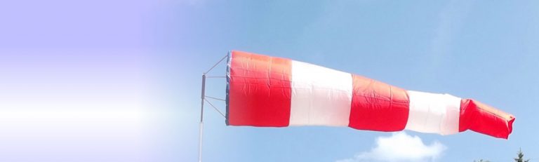 Red and white aviation windsock blows in the wind.